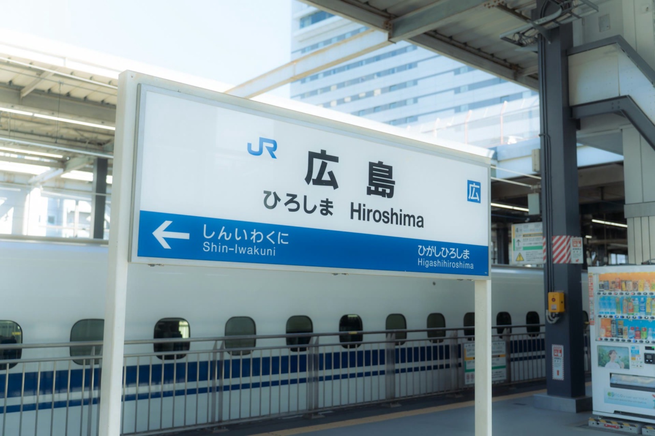 Papan nama Stasiun Hiroshima di samping kereta Shinkansen