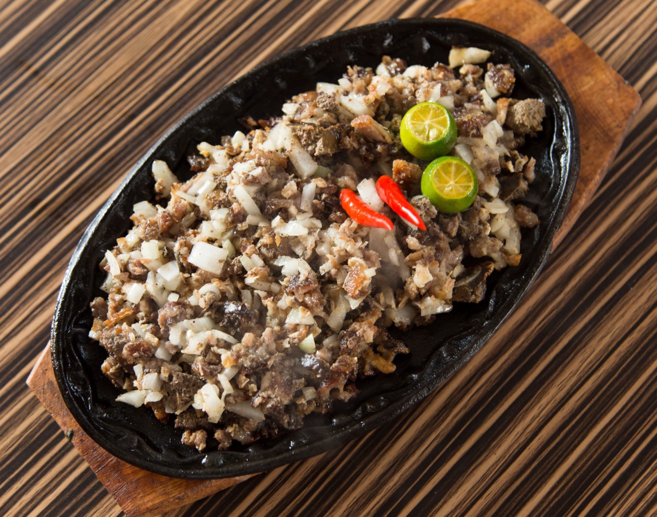 Sisig served on a plate with lime and chili