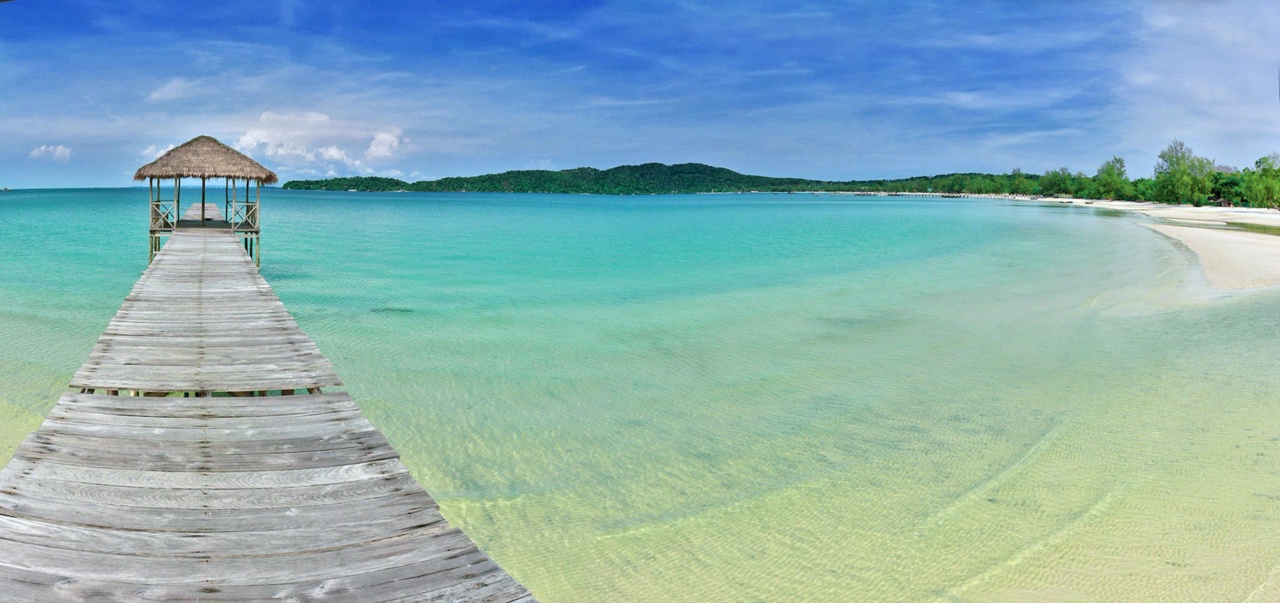 A wooden pier with a small thatched shelter over clear shallow water on Koh Rong Samloem