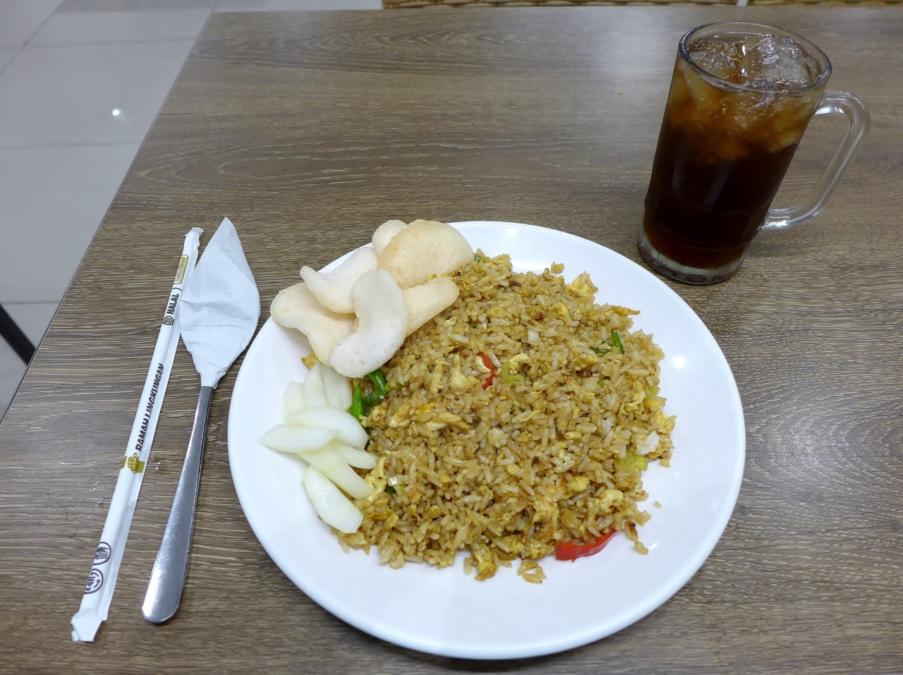 Nasi goreng avec des chips de crevettes et un verre de thé glacé