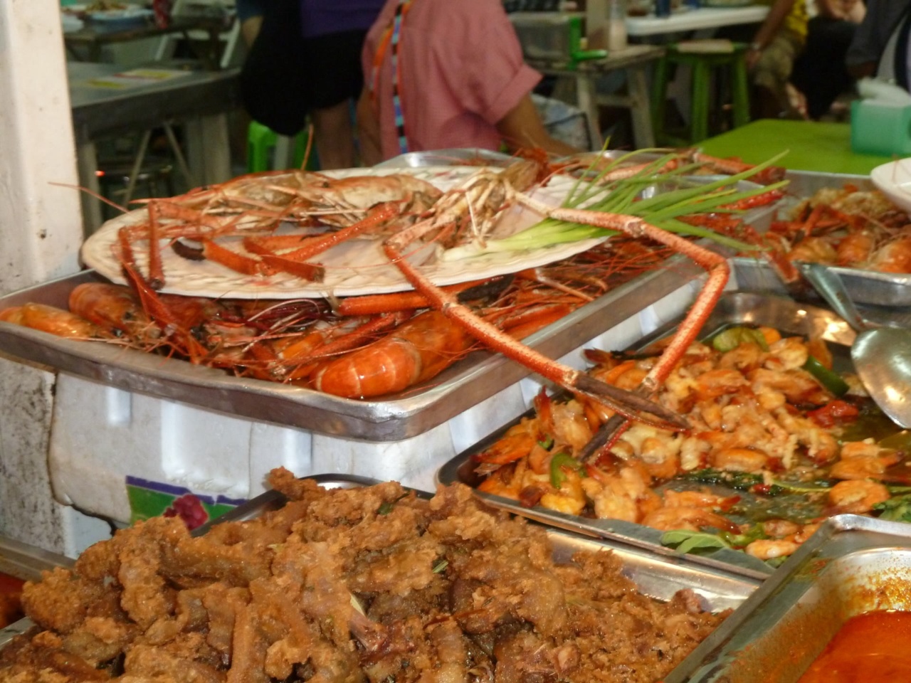 Trays of prawns and fried dishes at a food stall in the market