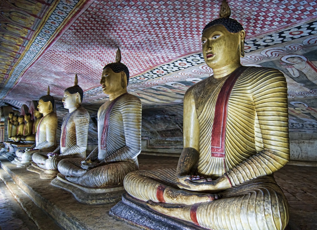 Seated Buddha statues beneath a painted cave ceiling at Dambulla