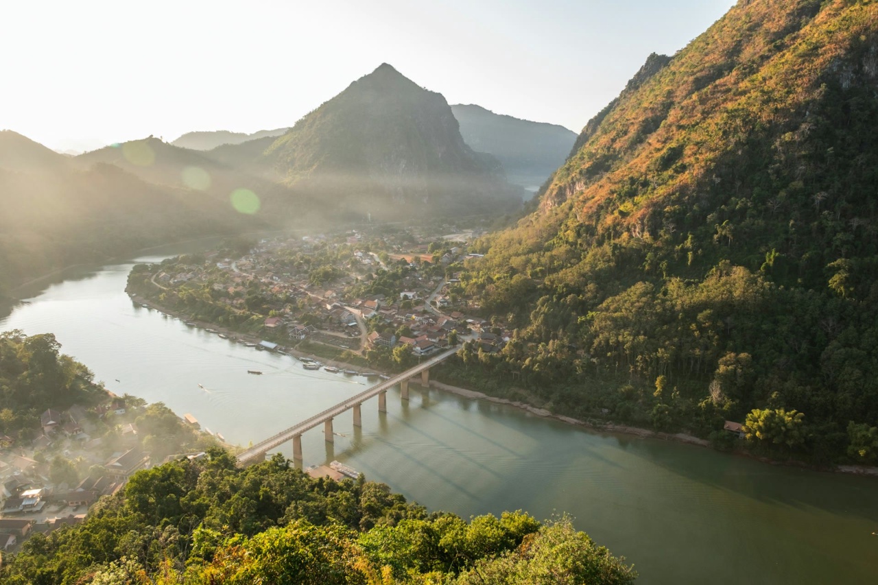 A river with a bridge below forested mountains at Nong Khiaw