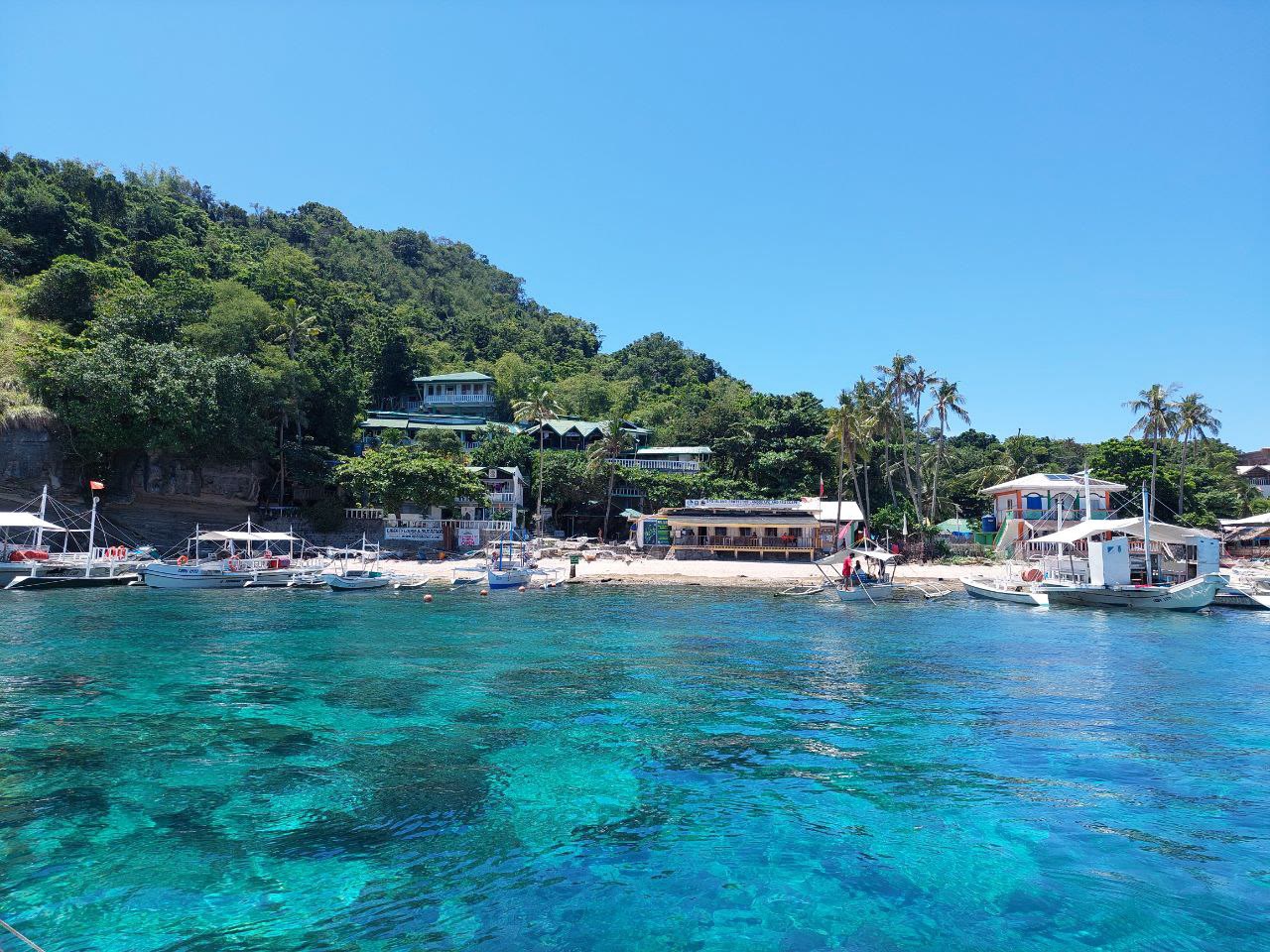 Pantai Pulau Apo dengan bot di air jernih