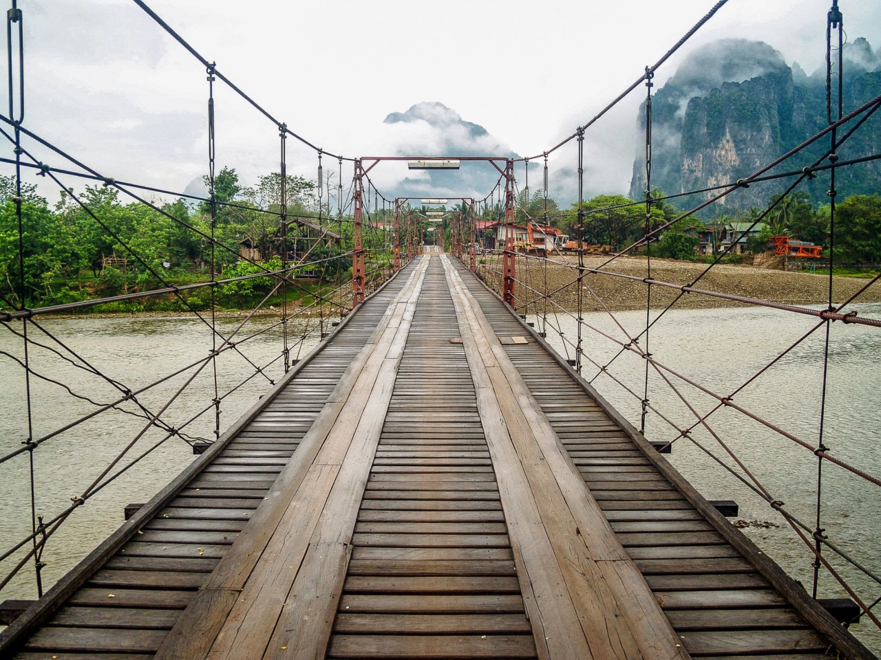 Un pont suspendu en bois au-dessus d’une rivière à Vang Vieng