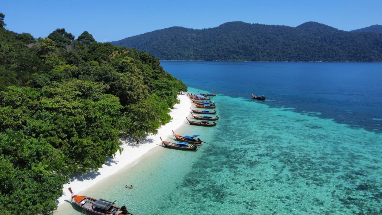 Longtail boats on the beach of Koh Lipe beside turquoise water