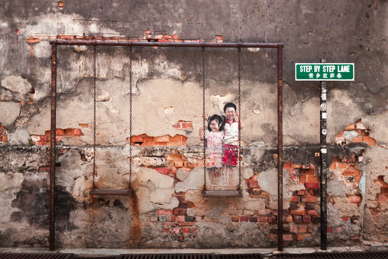 A mural of two children on a swing on a weathered brick wall in George Town